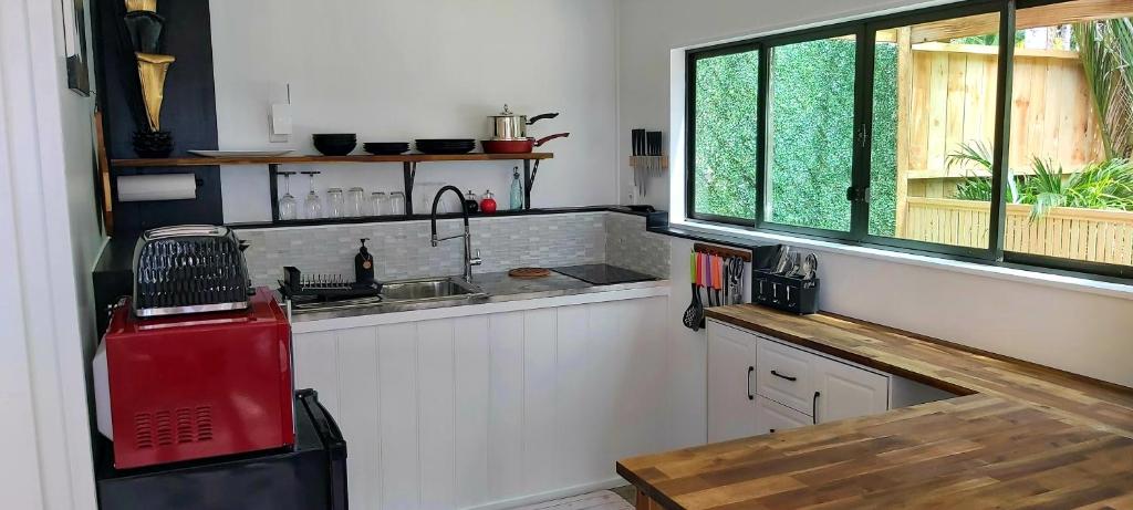 una cocina con fregadero y ventana en Darwin Cottage, en Kerikeri