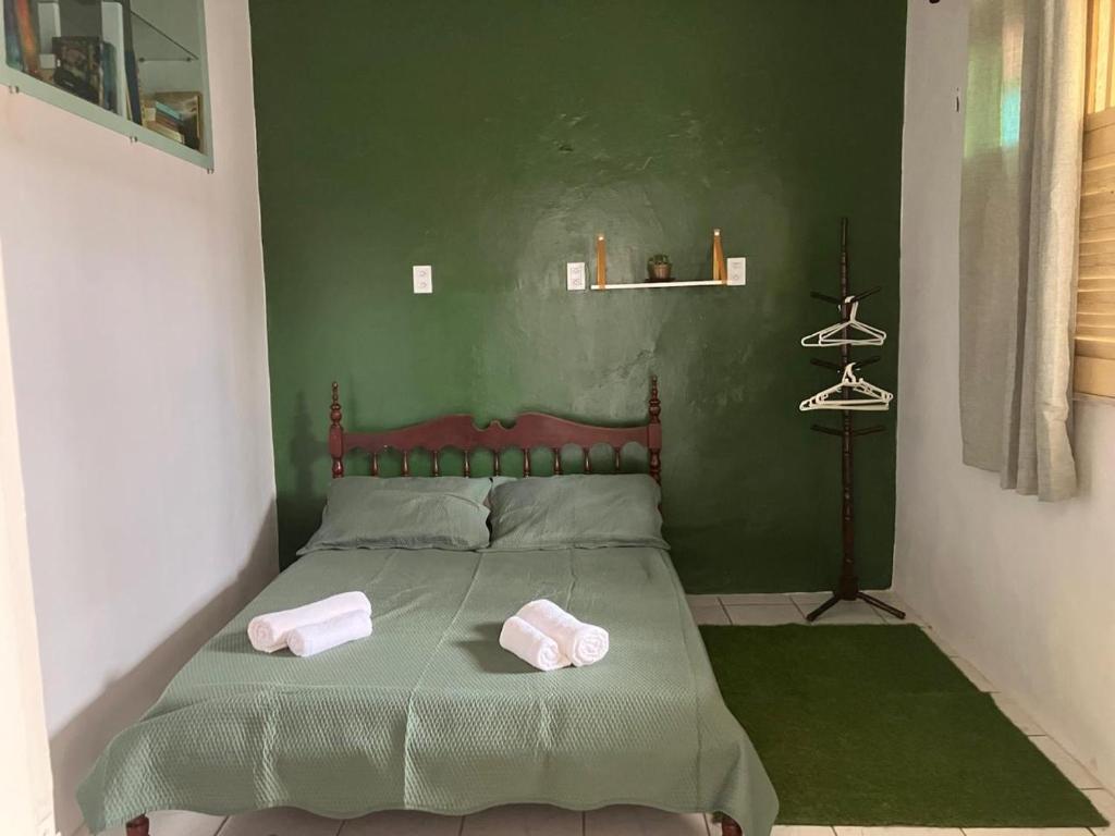 a green bedroom with a bed with two towels on it at Quarto aconchegante no centro in São Luís