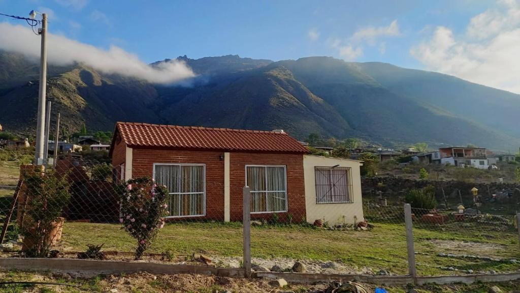 una piccola casa in un campo con montagne sullo sfondo di Cabaña Nuestro Quincho a El Mollar
