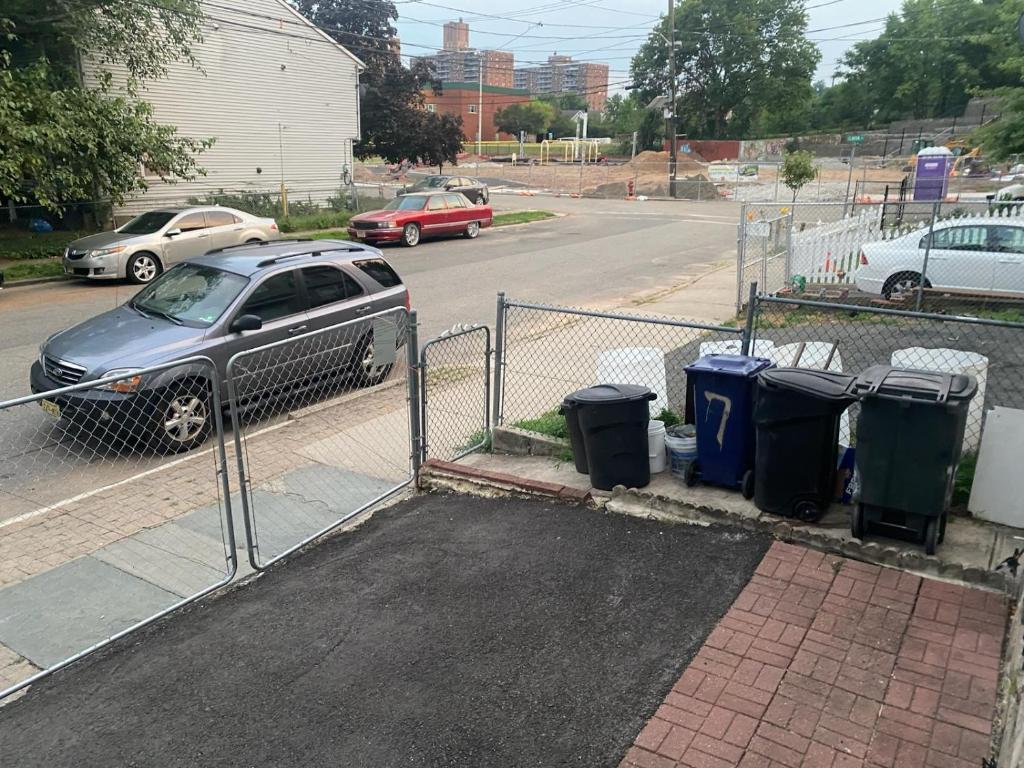 a car parked next to a fence with trash cans at private room in Paterson