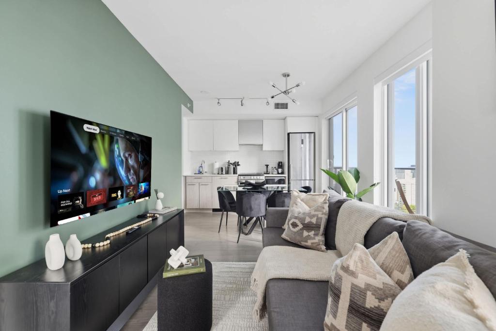a living room with a couch and a flat screen tv at Modern Downtown Retreat 3BR Condo with Patio in Toronto
