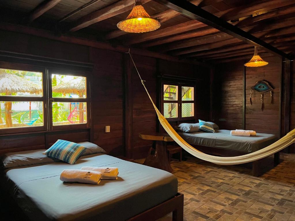 a room with two beds and a hammock in it at Cabañas Bacali in Bacalar