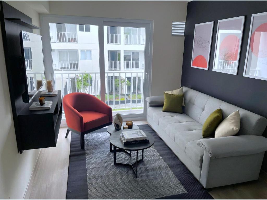 a living room with a couch and a red chair at Cozy 2BR Loft in the Heart of Miraflores in Lima