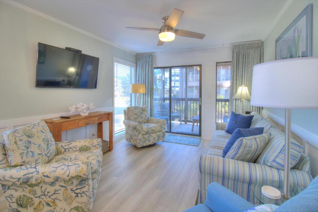 ein Wohnzimmer mit Sofa, Sesseln und Fernseher in der Unterkunft Tilghman Beach & Racquet Club - 114 in Myrtle Beach