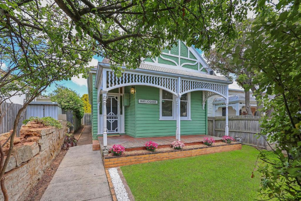 una casa verde con porche y valla en Minty, en Warrnambool