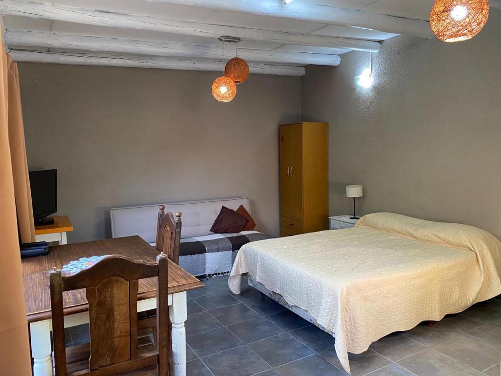 a bedroom with two beds and a table and a tv at Armonía y plenitud in Trelew