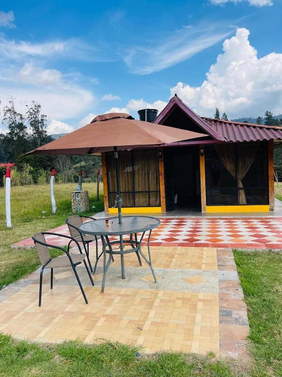 a table and chairs and an umbrella in front of a house at Cabaña Viento Sereno in Tibaná