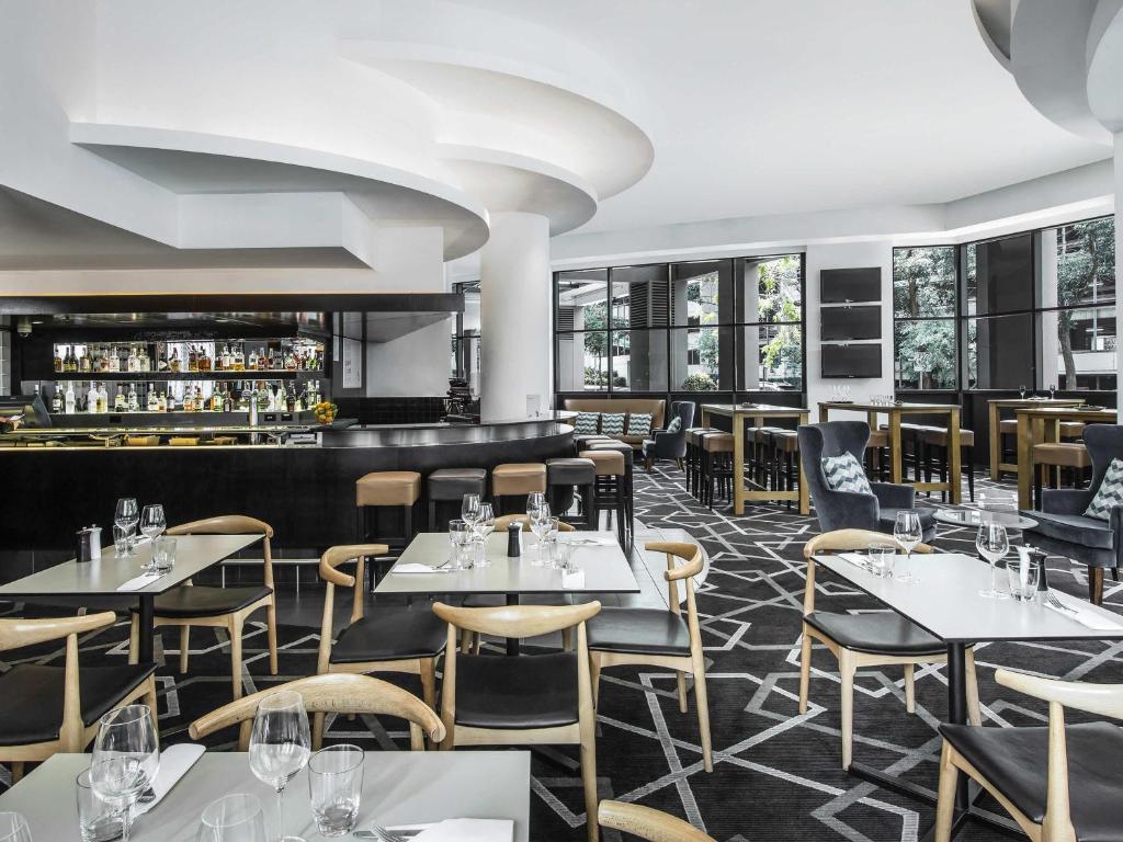 a restaurant with tables and chairs and a bar at Mantra Parramatta in Sydney