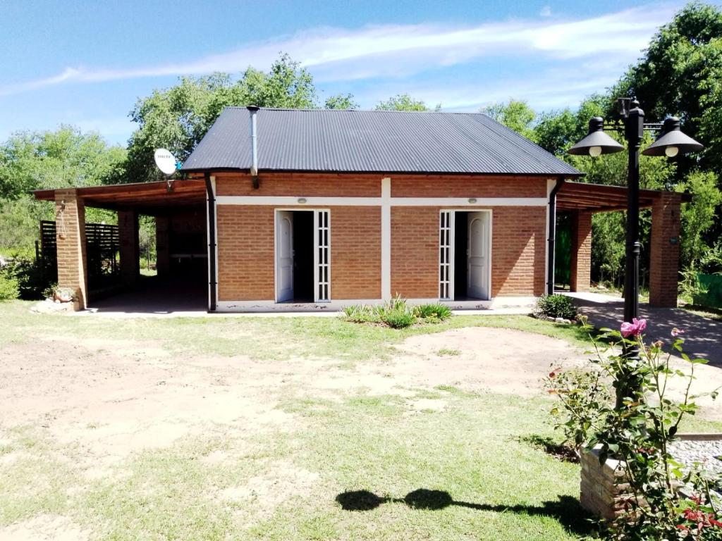 a small brick house with a black roof at Aguaribay Cabañas in Arroyo de Los Patos