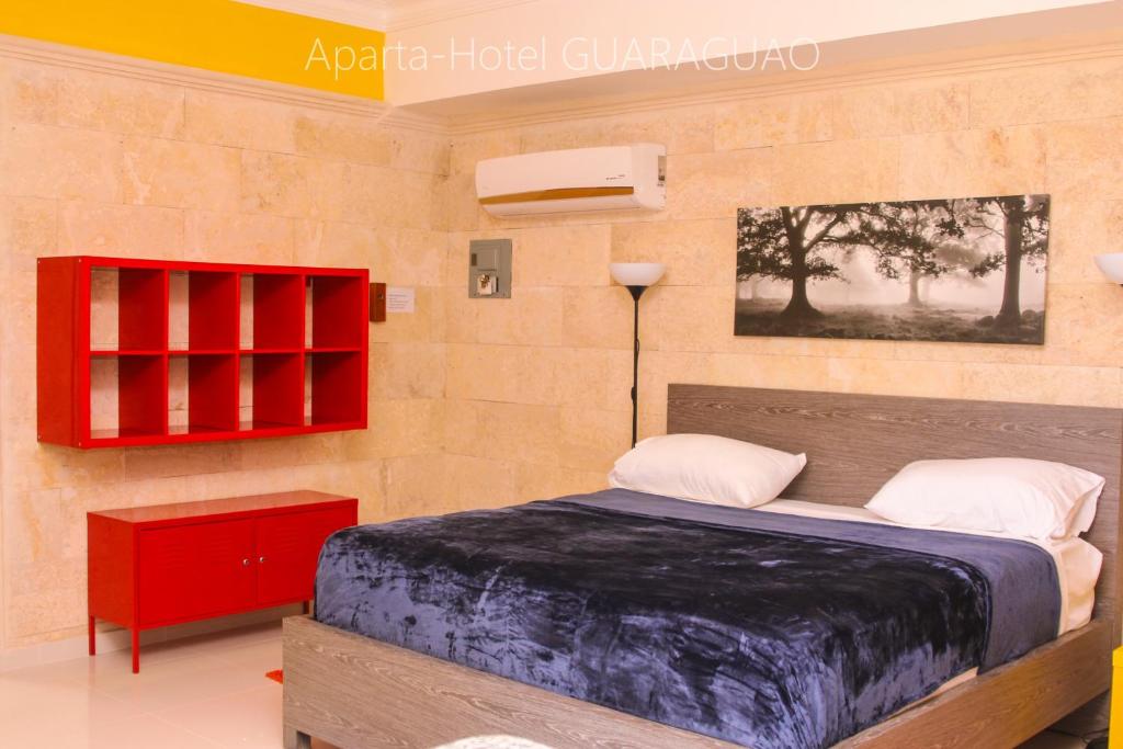 um quarto com uma cama e um armário vermelho em Apartahotel Guaraguao em San Pedro de Macorís