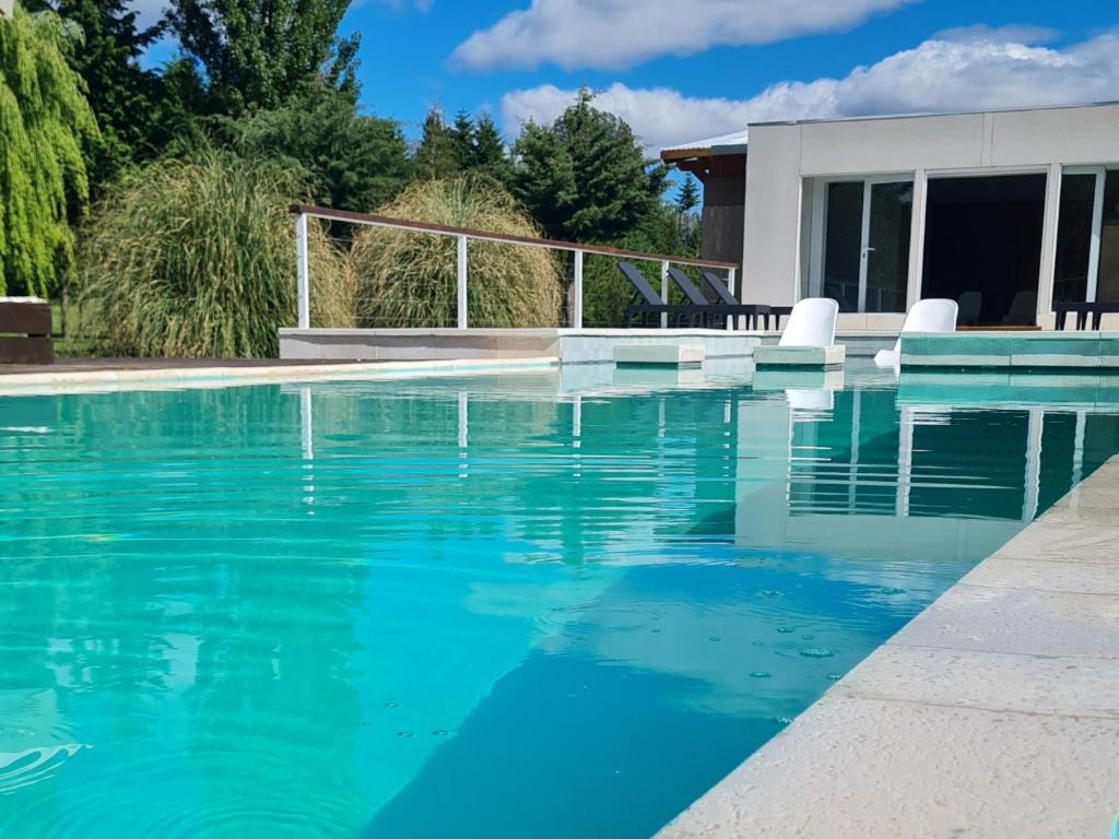 einen Pool mit blauem Wasser vor einem Haus in der Unterkunft Las Nubes in El Bolsón