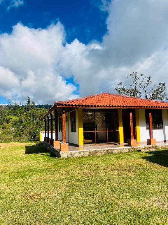 a small building with a red roof on a field at Cabaña Brisa Andina in Tibaná