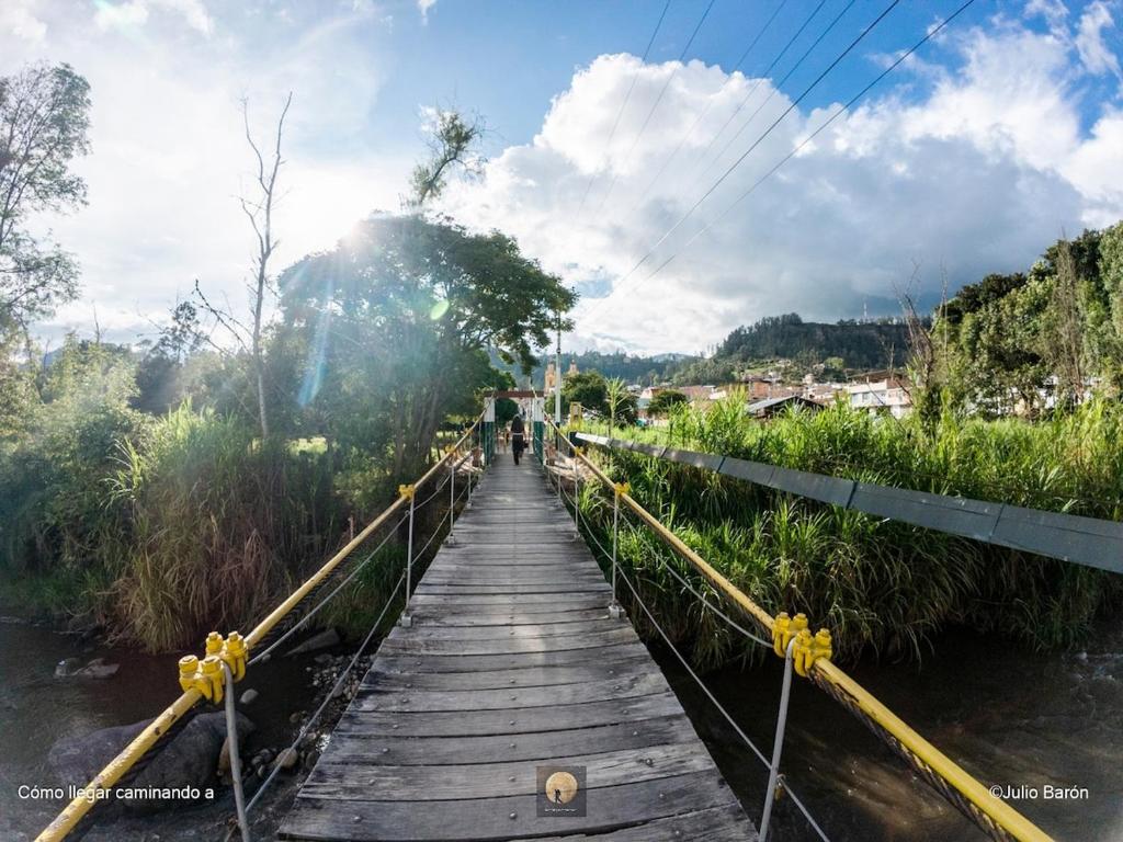 a bridge over a river with a person walking on it at Cabaña Brisa Andina in Tibaná