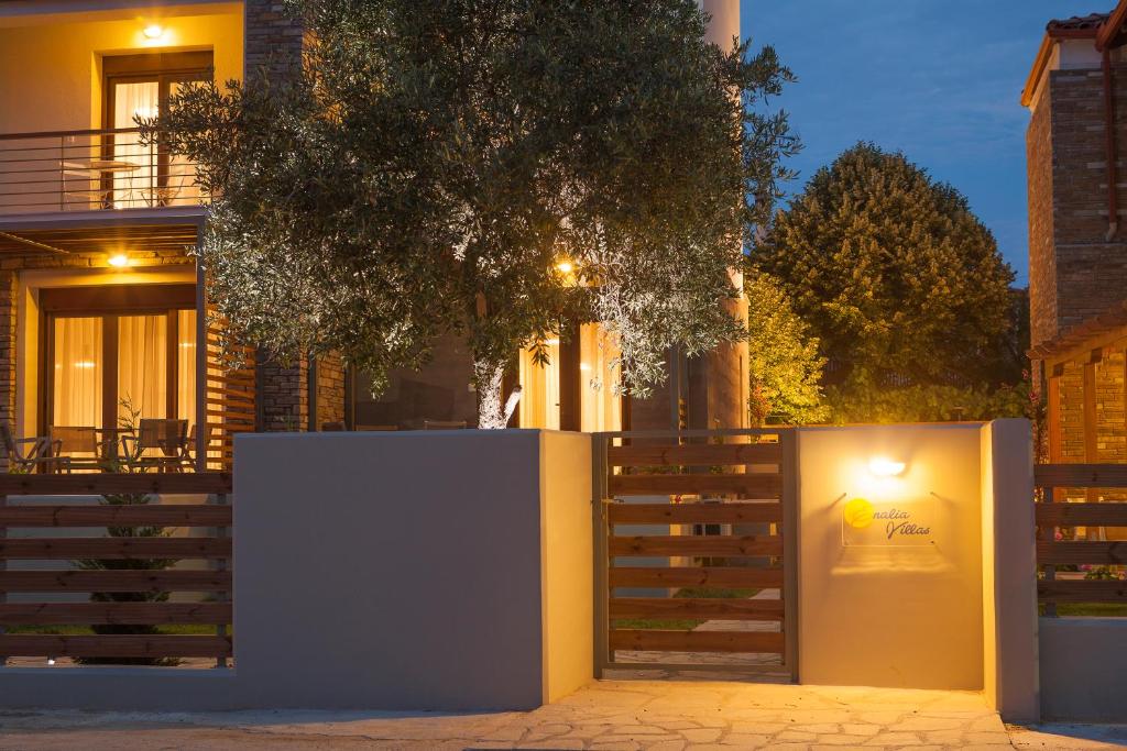 a fence in front of a house with a tree at Enalia Villas in Ierissos