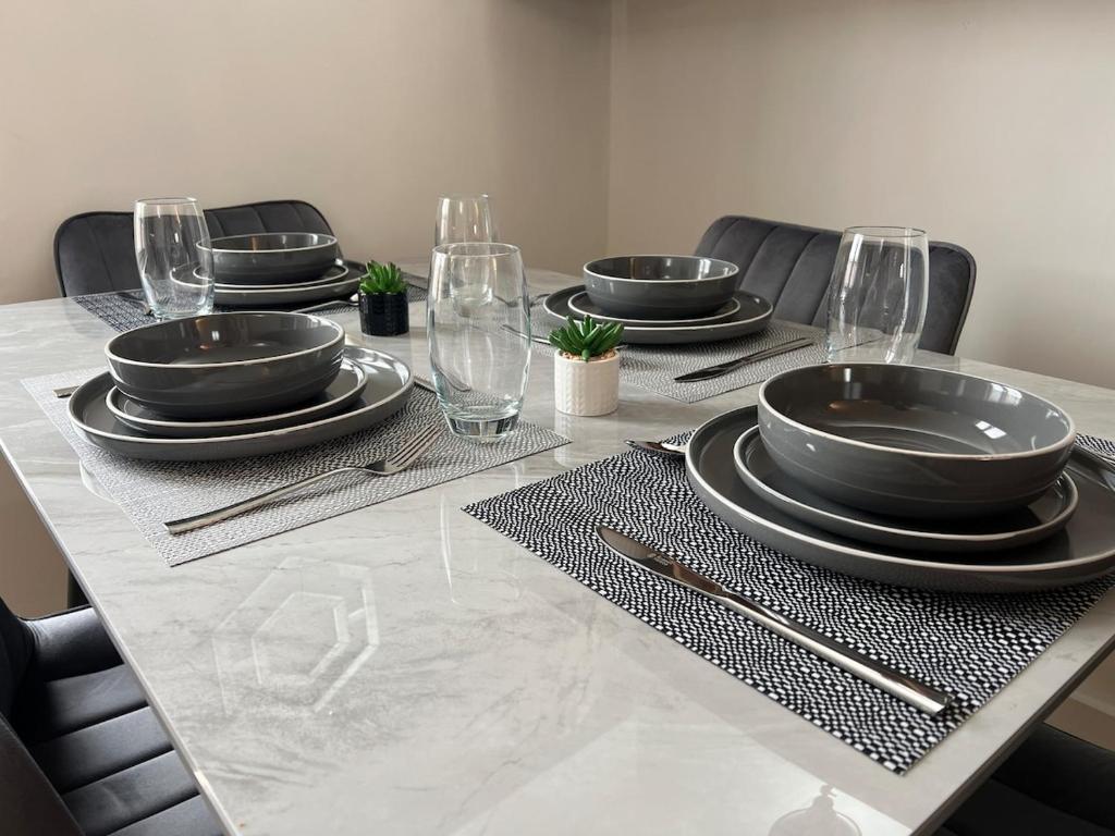 a dining room table with plates and glasses on it at Duplex Apartment in Greater Manchester in Oldham