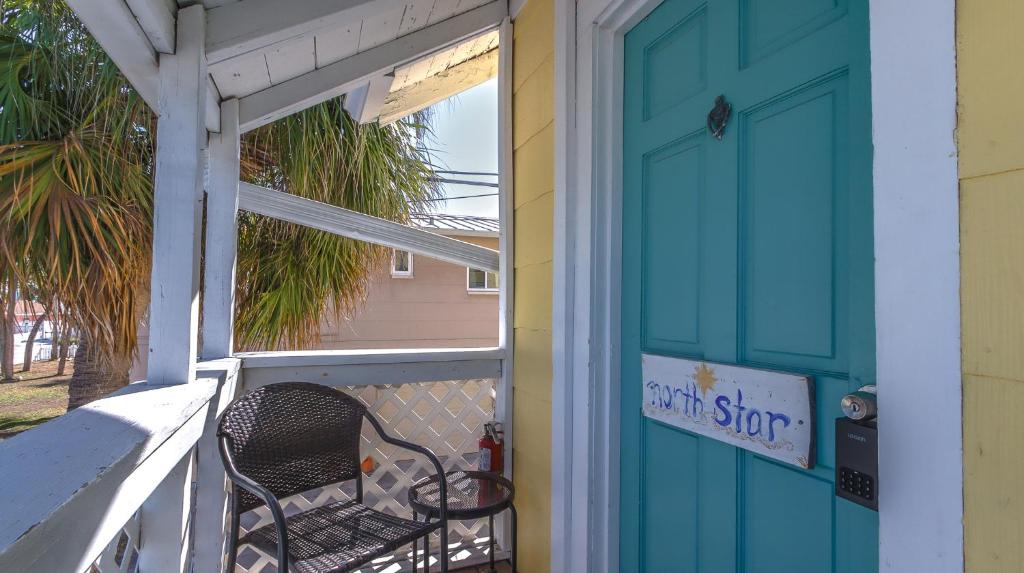 a porch with a blue door and a chair at 1BR 1BA NorthStar Bungalow. Just Steps to the beach and the bay. in St Pete Beach
