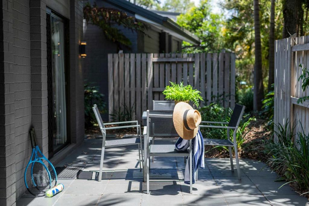 Bayshore Bungalow 12 - Oceanstays في خليج بايرون: فناء به كرسيان وقبعة عليه