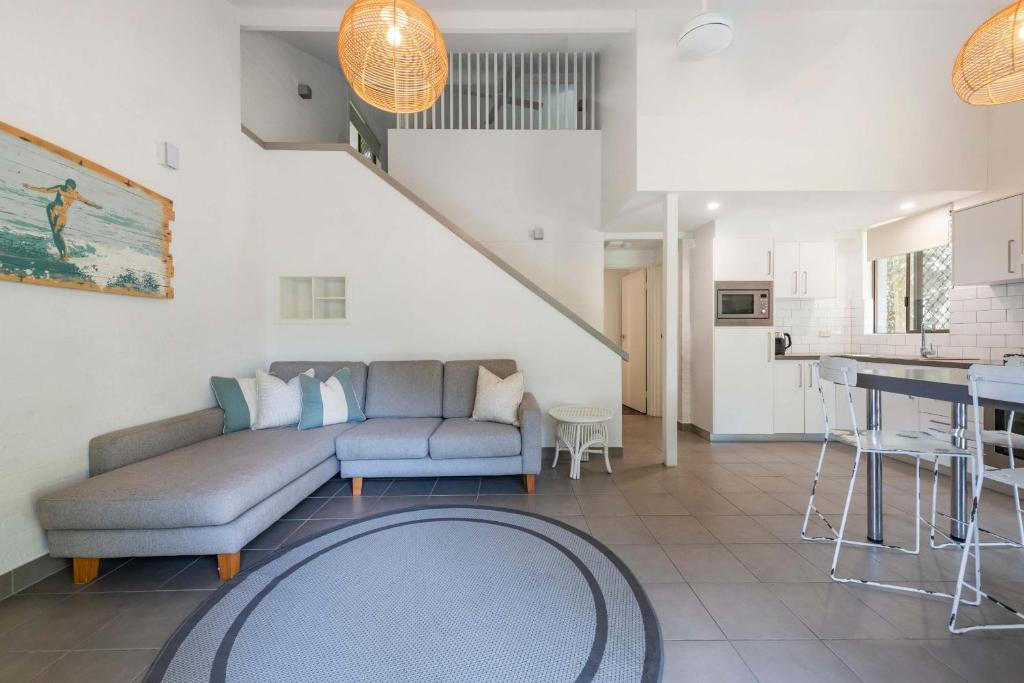 Bayshore Bungalow 13 - Oceanstays في خليج بايرون: غرفة معيشة مع أريكة ومطبخ