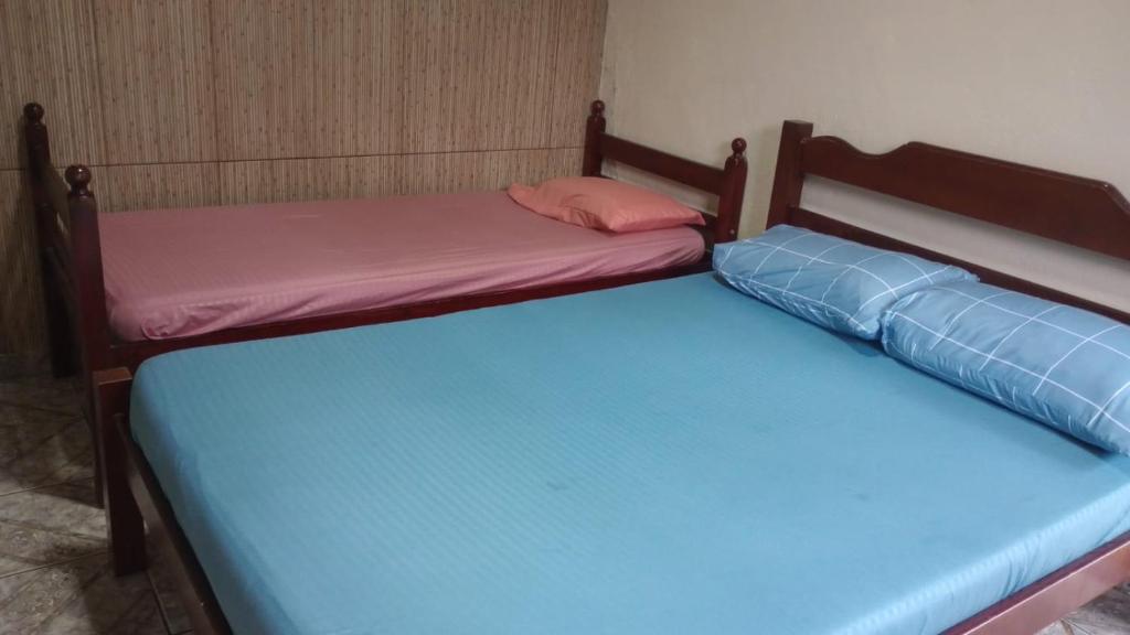 two beds in a room with blue and pink at Casa da alegria in Ubatuba