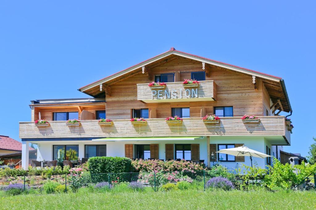 ein großes Holzhaus mit einem Balkon und Blumen in der Unterkunft Pension Reiter-Moravec in Seewalchen