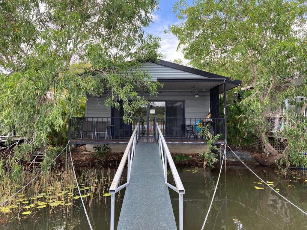 a small house on a river with a bridge at Black Wattle Bungalow 30 Lake Bennett in Lake Bennett