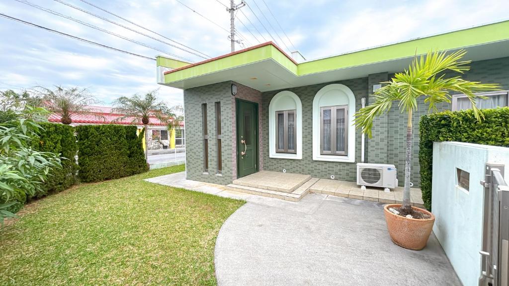 una pequeña casa con un verde y blanco en Green Lodge, en Yomitan