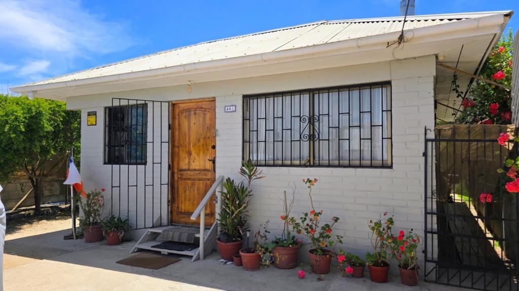 Encantadora Casa con Balcón a Pasos del Mar في لاس كروسيس: بيت أبيض صغير به باب ونباتات في أصص