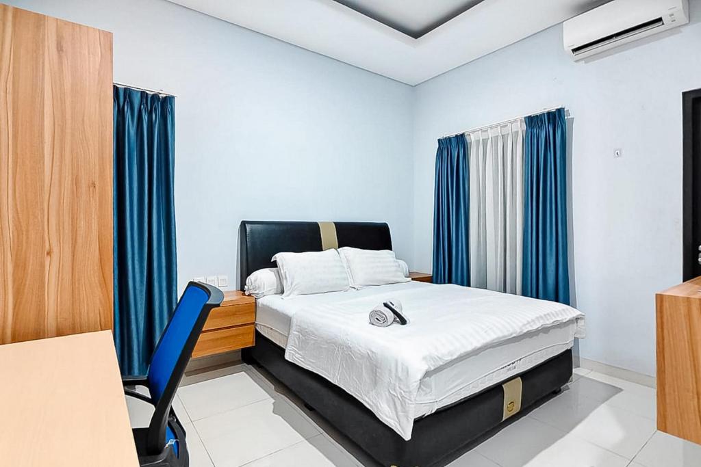 a bedroom with a bed with blue curtains and a desk at Grace House Syariah Cikarang RedPartner in Jatirarangan