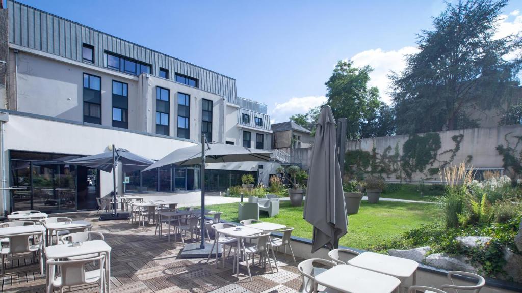 a patio with tables and umbrellas in front of a building at Campanile Limoges Centre - Gare in Limoges