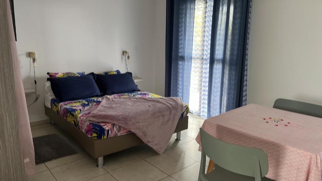 sypialnia z łóżkiem z niebieskimi poduszkami i stołem w obiekcie Les Zamours Des Lianes w mieście Saint-Joseph