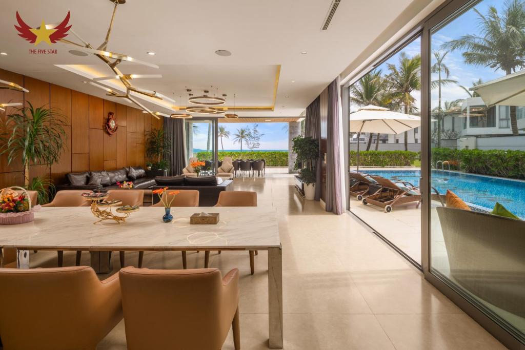 an open living room with a table and a pool at The Five Stars Villa 7 Bedrooms Beachfront in Danang