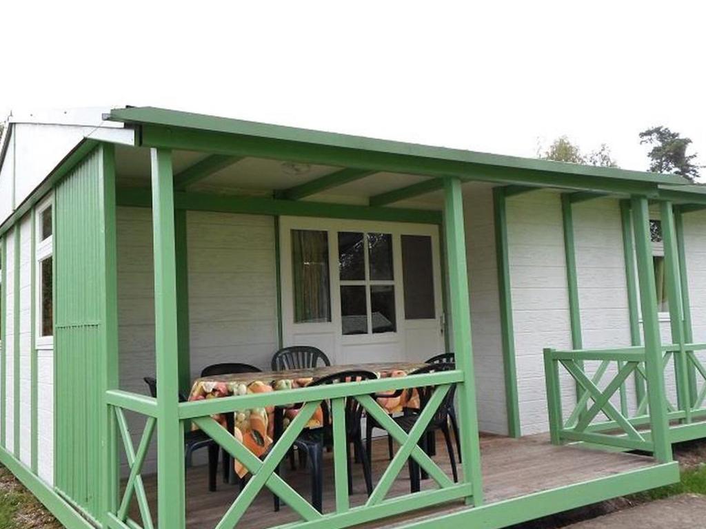 a green shed with a table on a deck at Chalet 3 Chambres avec Terrasse - Parfait pour 6 Personnes - API-1-52-991 in La Chapelle