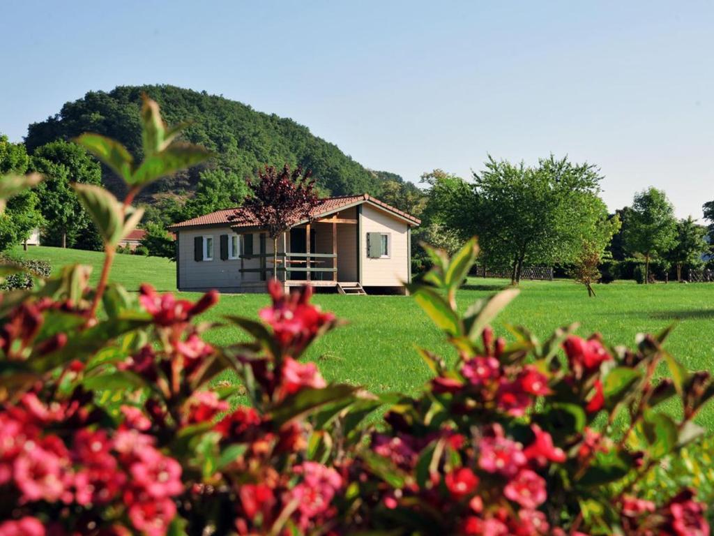 a small house in the middle of a field with flowers at Chalet pour 6 pers avec terrasse au Domaine du Lac de Champos - API-1-52-1001 in Charmes-sur-lʼHerbasse