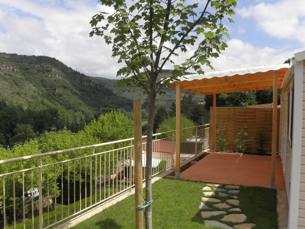 Mobil-home 28m² avec terrasse à Saint-Rome-de-Tarn - API-1-52-993 في Saint-Rome-de-Tarn: شرفة بها عريشة خشبية وشجرة