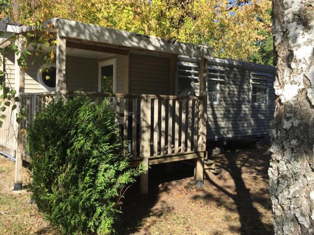 a log cabin with a porch next to a tree at Mobil-home 38m² avec terrasse pour 6 personnes - API-1-52-1008 in Luynes