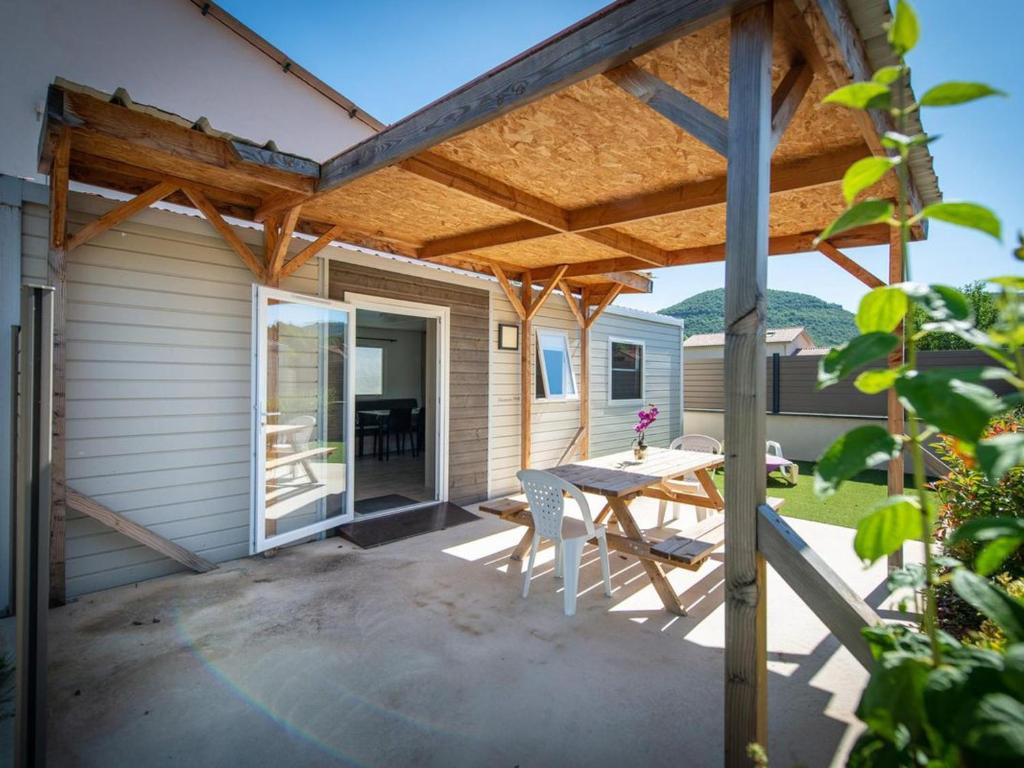 un patio con una pérgola de madera y una mesa en Mobil-home PMR avec Terrasse à Saint-Rome-de-Tarn - API-1-52-1012, en Saint-Rome-de-Tarn