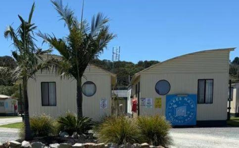 un piccolo edificio con una palma di fronte di Lakes Main Holiday Park a Lakes Entrance