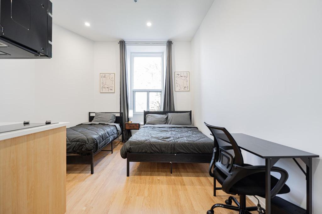 een kamer met 2 bedden, een bureau en een tafel bij Central Studio For 3 Guest With Parking in Montreal