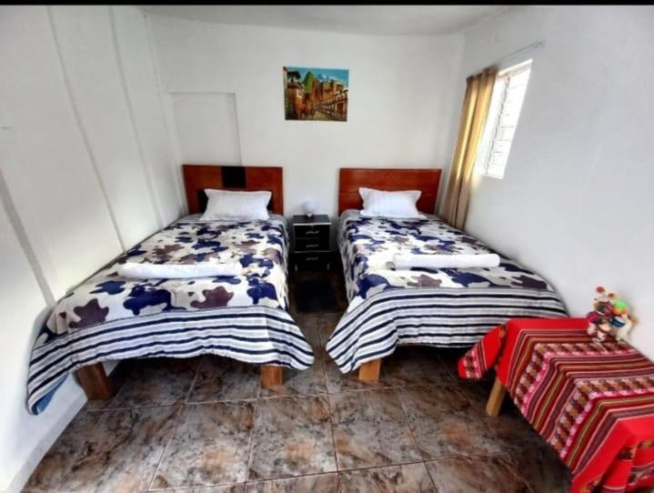 een slaapkamer met 2 bedden en een tafel bij Casa Hospedaje Sunya in Cuzco