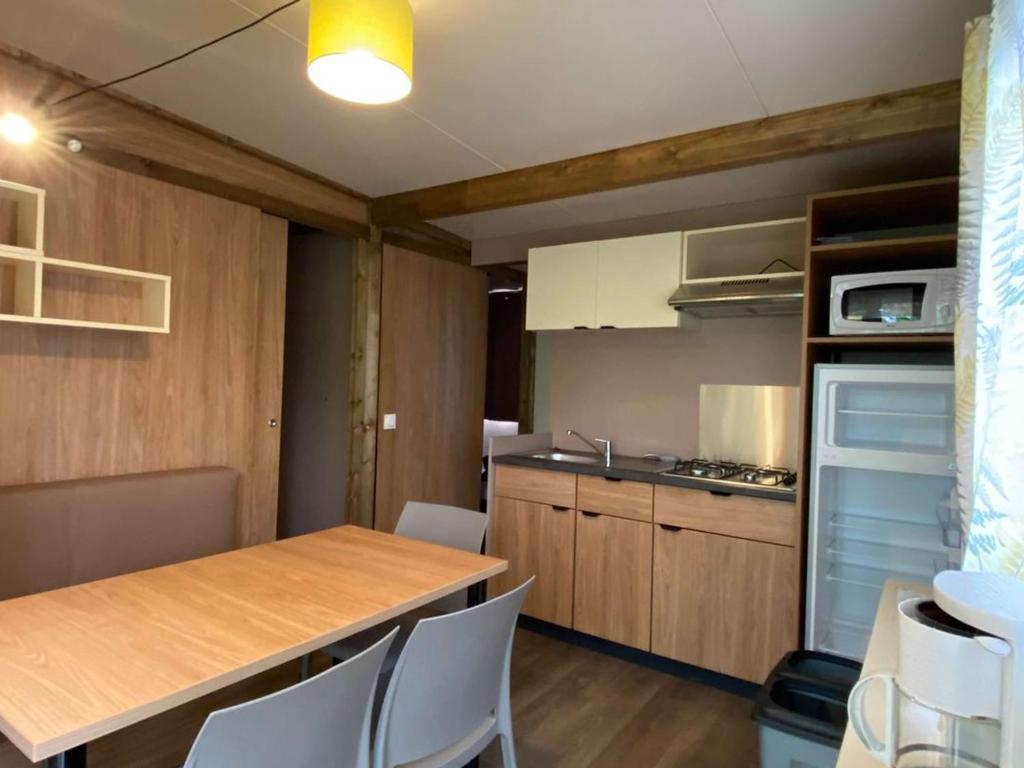 Chalet avec Terrasse à Soubès - 3 personnes - API-1-52-1057 في Soubès: مطبخ مع طاولة خشبية وكراسي بيضاء