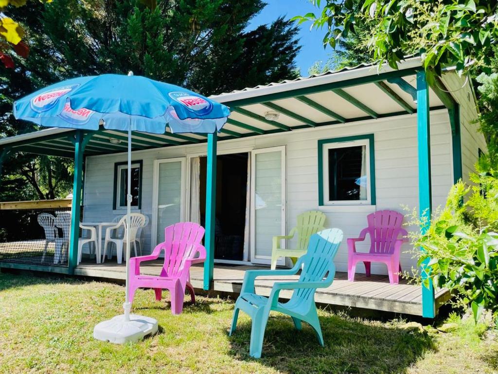 a group of colorful chairs and an umbrella on a porch at Chalet Confort 6 Pers - Terrasse - API-1-52-1032 in Belloc