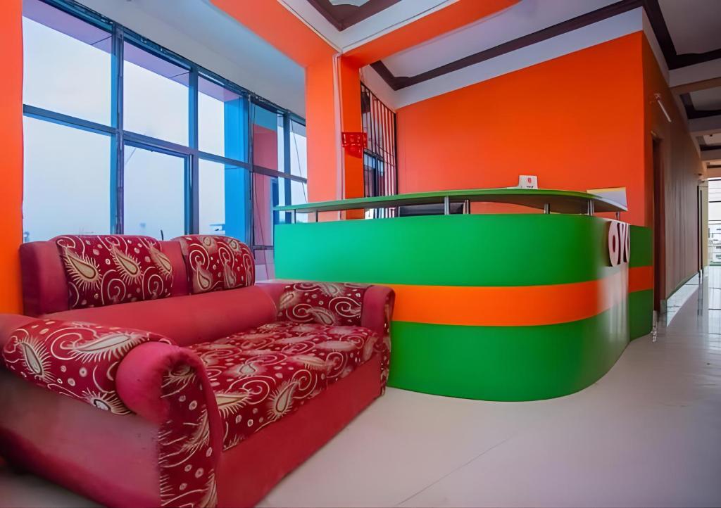 Sumeru Hotel and Lodge في Itahari: غرفة معيشة مع أريكة وجدران برتقالية وأخضر