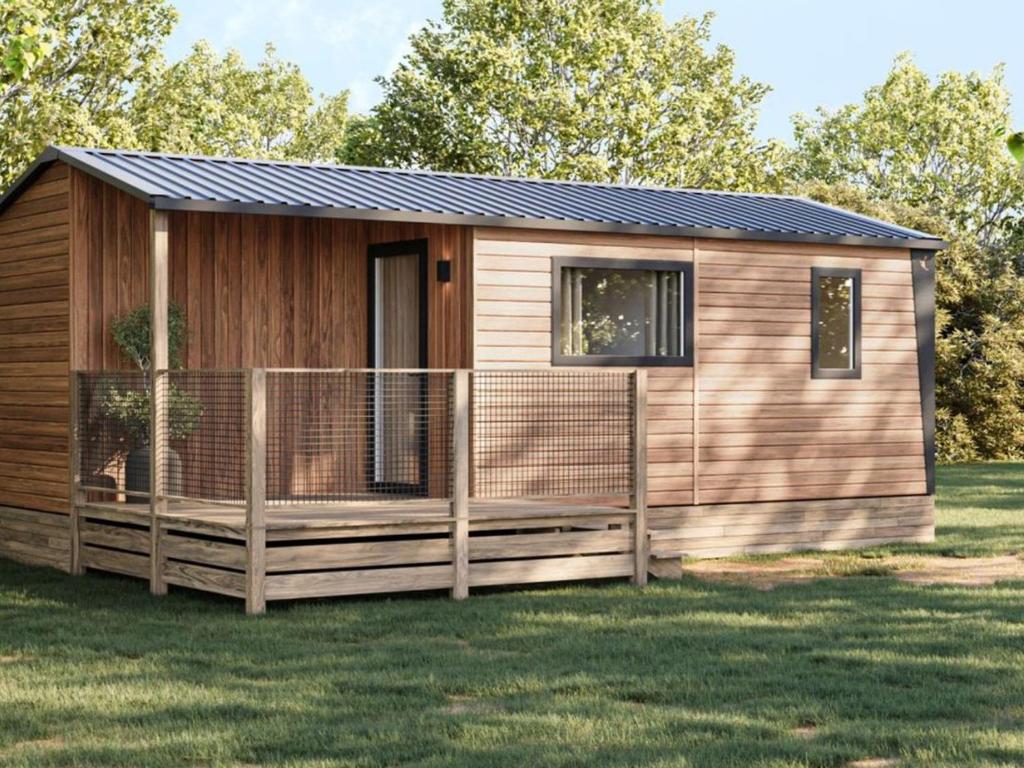 Mobile home avec Terrasse à Saint-Rome-de-Tarn - API-1-52-1049 في Saint-Rome-de-Tarn: كابينة فيها سور خشبي على العشب