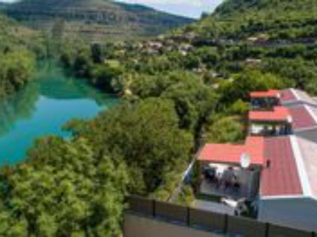 a house with a red roof and a river at Mobil-home cosy avec terrasse pour 5 personnes - API-1-52-1066 in Saint-Rome-de-Tarn