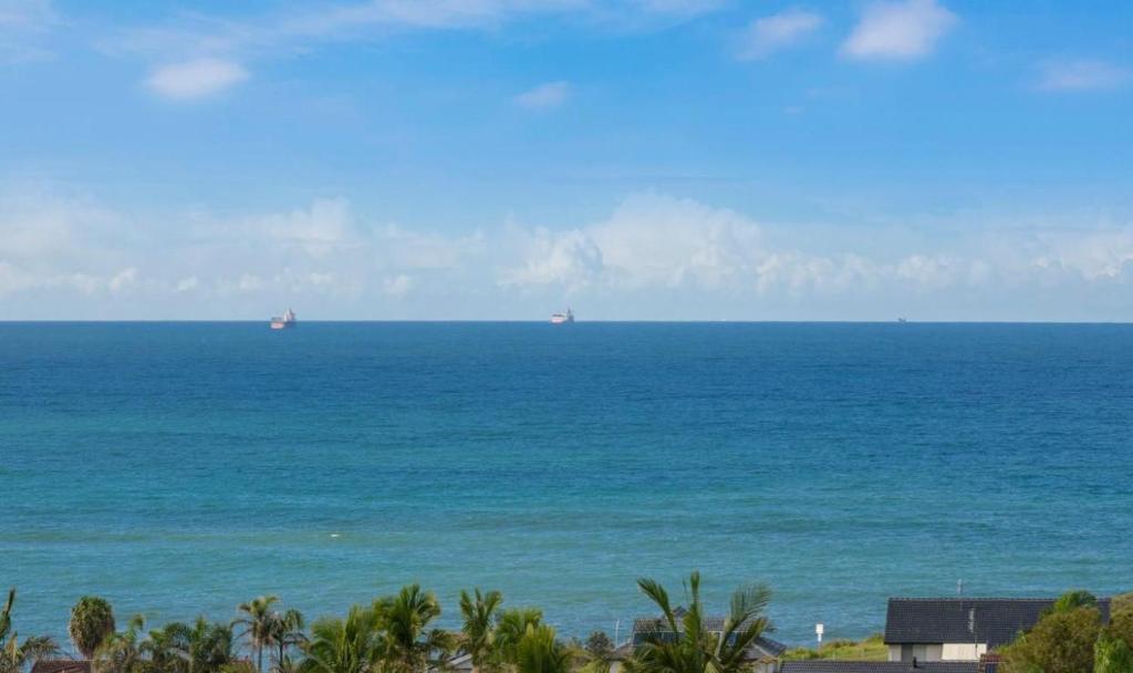 een uitzicht op de oceaan met schepen in de verte bij Oceans 21 Caves Beach in Caves Beach