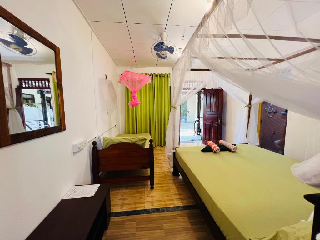 a bedroom with a green bed and a chair at Ancient Tree in Mirissa