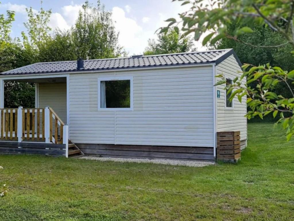 a small white shed with a porch in a yard at Mobil-home cosy avec terrasse à Loudéac - API-1-52-1116 in Loudéac
