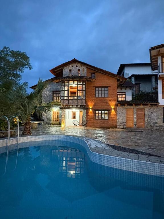 a house with a swimming pool in front of it at Cabañas Las Camelias in Cuetzalán del Progreso