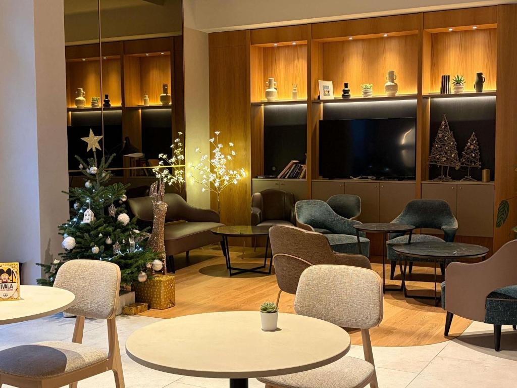 a waiting room with a christmas tree and tables and chairs at Mercure Colmar Centre Unterlinden in Colmar