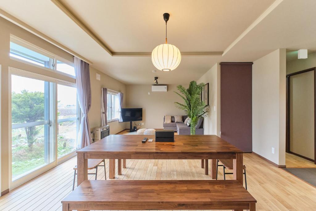 a living room with a wooden table and a large window at Casa Katatsumuri in Nakafurano
